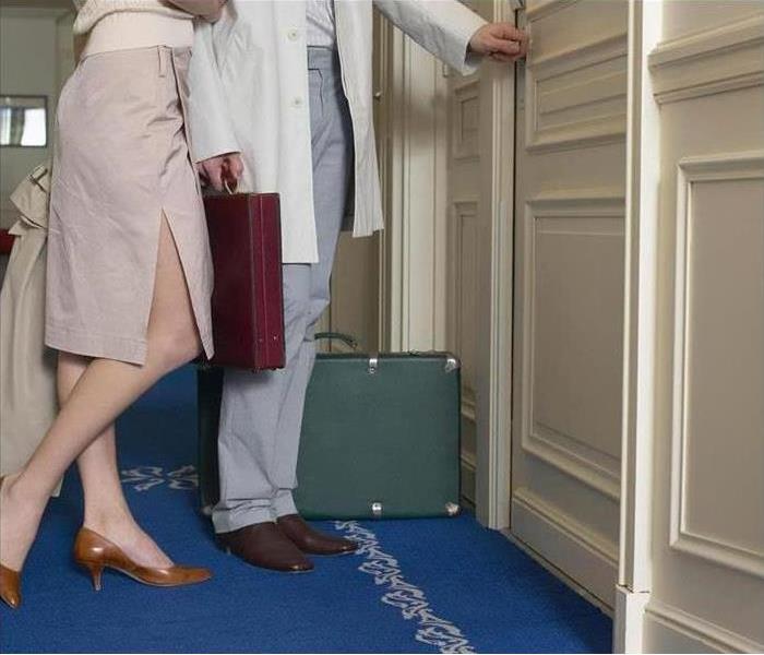 A couple with luggage entering a hotel room.